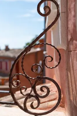 a metal bench sitting on the side of a window at Maison d'hôtes Une hirondelle en Provence in Roussillon