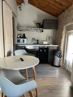 a kitchen with a table and chairs in a room at Petit studio Le Pigeonnier à 5 mn de Lourmarin in Puyvert
