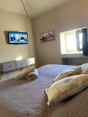 a bedroom with a bed with pillows and a tv on the wall at Petit studio Le Pigeonnier à 5 mn de Lourmarin in Puyvert