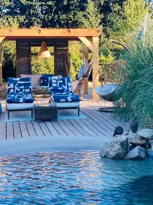 a gazebo with blue couches on a deck near the water at Le Nid de la Huppe in Noves