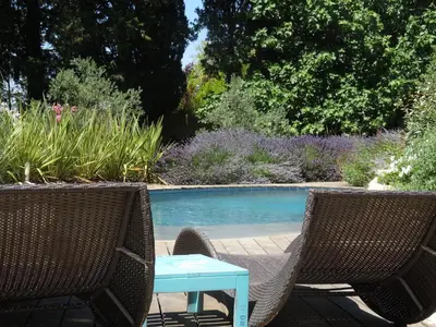 two chairs and a table next to a swimming pool at Le Nid de la Huppe in Noves