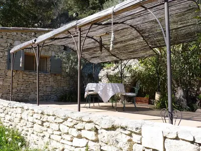 a patio with a table and chairs under a roof at La Baumo 1 und 2 in Le Beaucet