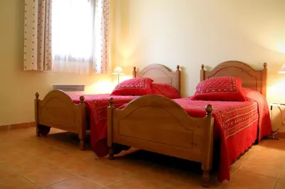 a bedroom with two beds with red pillows at Le Relais Du Grand Logis in Mirabeau