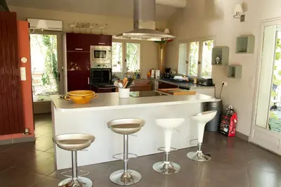 a kitchen with a white counter and stools in it at maison près de l'eau in LʼIsle-sur-la-Sorgue