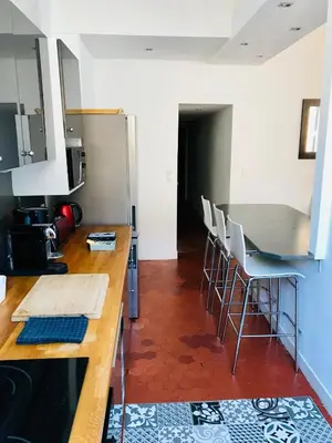a kitchen with a counter with chairs and a refrigerator at Appartement coeur historique Aix in Aix-en-Provence