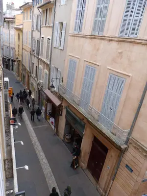 a group of people walking down a street with buildings at Appartement coeur historique Aix in Aix-en-Provence