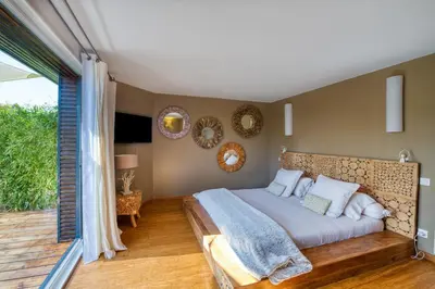a bedroom with a large bed and a balcony at Mas des Cigales in Eygalières