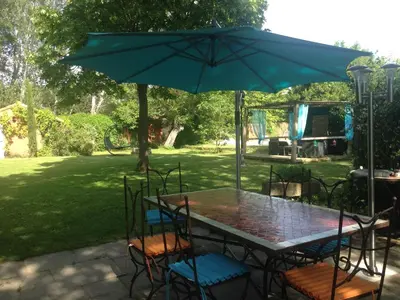 a table and chairs under a large umbrella at Le Mas des Platanes in Entraigues-sur-la-Sorgue