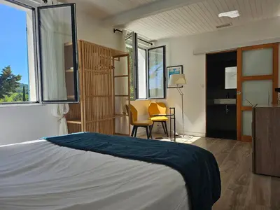 a bedroom with a bed and a table and a chair at La Luberonne in Lourmarin