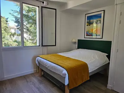 a bedroom with a bed and two windows at La Luberonne in Lourmarin