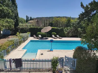 a swimming pool with an umbrella and chairs at La Luberonne in Lourmarin