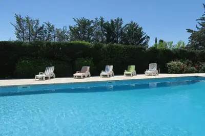 a group of lounge chairs sitting next to a swimming pool at La Luberonne in Lourmarin