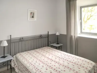 a bedroom with a bed with two nightstands and a window at Maison charmante à Oppède avec piscine partagée in Oppède