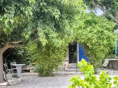a blue door with a table and chairs under a tree at Maison charmante à Oppède avec piscine partagée in Oppède