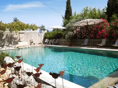 a swimming pool with an umbrella and some flowers at Appartement accueillant avec piscine à Oppède 70 m², vue montagne in Oppède