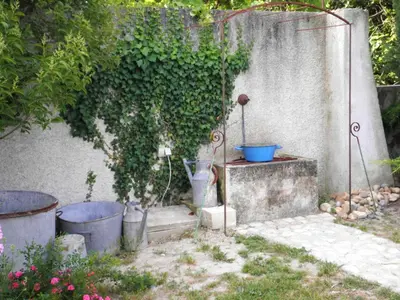 a garden with two potted plants and a wall at Appartement accueillant avec piscine à Oppède 70 m², vue montagne in Oppède