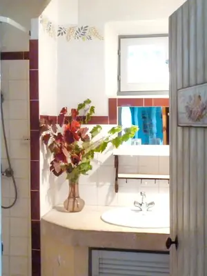 a bathroom with a sink and a vase of flowers at Appartement accueillant avec piscine à Oppède 70 m², vue montagne in Oppède