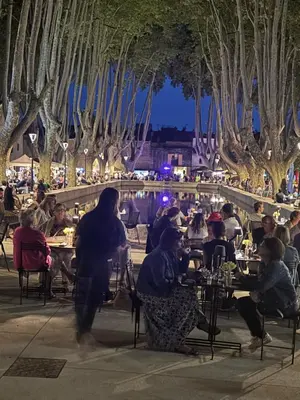a group of people sitting at tables at night at Luberon maison de village entière 2 à 6 personnes in Cabrières-dʼAigues