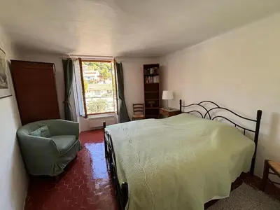 a bedroom with a bed and a chair and a window at Luberon maison de village entière 2 à 6 personnes in Cabrières-dʼAigues