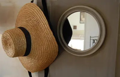 a straw hat hanging on a wall with a mirror at Cyprès du Paradis à Gordes in Gordes