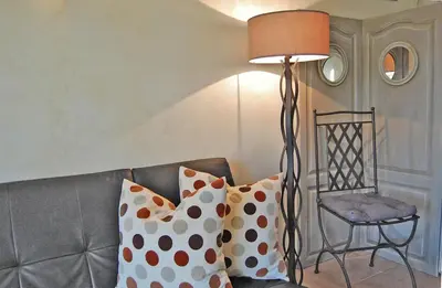 a floor lamp sitting next to a couch with pillows at Cyprès du Paradis à Gordes in Gordes