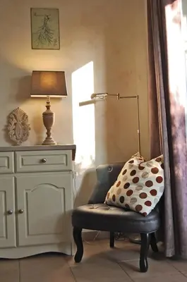 a room with a chair and a lamp and a dresser at Cyprès du Paradis à Gordes in Gordes