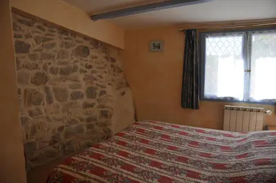 a bedroom with a bed with a stone wall at Le Petit Labouret in Revest-du-Bion