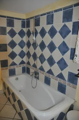 a bath tub in a bathroom with blue and white tiles at Le Petit Labouret in Revest-du-Bion