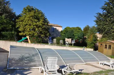 a swimming pool with two chairs and a glass roof at Le Petit Labouret in Revest-du-Bion