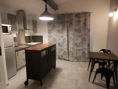 a kitchen with a counter and a table and a refrigerator at Mas les vieux chênes in Lambesc