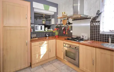 a kitchen with wooden cabinets and a stove top oven at Beautiful Home In Maubec in Maubec