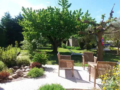 a garden with three chairs and a table and a tree at Maison de charme avec piscine privée à Velleron in Velleron