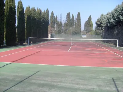a tennis court with a net and some trees at Les grands pins in Saint-Andiol