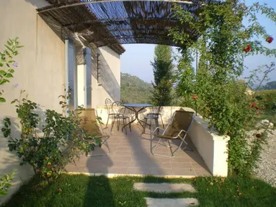 a patio with chairs and a table with an umbrella at Cerise en Provence in Venasque