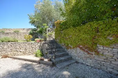 a stone wall with a staircase next to a brick wall at Cerise en Provence in Venasque