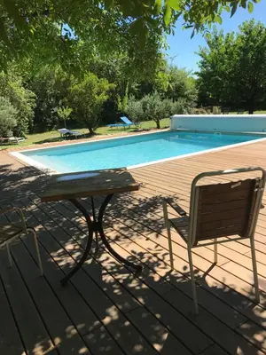 a table and a chair next to a swimming pool at L'atelier des Coudelières in Le Thor
