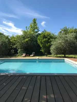 a swimming pool with a wooden deck at L'atelier des Coudelières in Le Thor