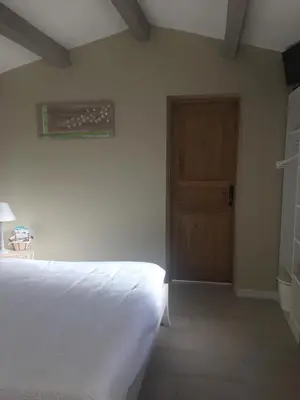 a bedroom with a white bed and a wooden door at L'atelier des Coudelières in Le Thor