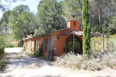 an orange building with a tree next to a dirt road at La Petite Yolande in Aix-en-Provence