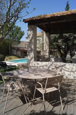 a table and chairs on a patio with a pool at Domaine de la Girafe in Eyragues