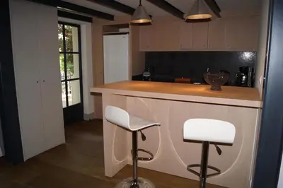 a kitchen with a bar with two white stools at Domaine de la Girafe in Eyragues