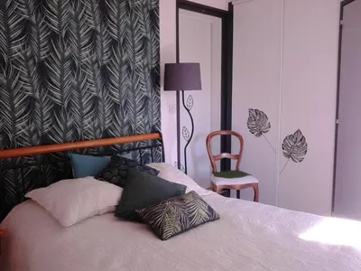 a bedroom with a bed with a chair and a table at Les Florides in LʼIsle-sur-la-Sorgue