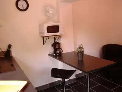 a room with a table and a microwave on a wall at Les Florides in LʼIsle-sur-la-Sorgue