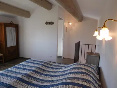 a bedroom with a bed with a blue striped blanket at Le Petit Mas des Hauts de Beyssan, Maison de vacances avec piscine privative pour 2 personnes in Gargas