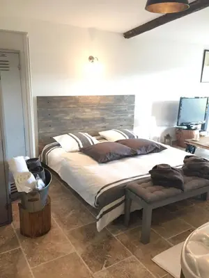a bedroom with a large bed with a wooden headboard at Au Havre De Paix sainte victoire vauvenargues in Vauvenargues
