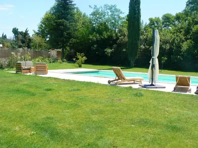 a pool with two lawn chairs and an umbrella at Villa charmante à Eyragues avec piscine privée in Eyragues