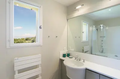 a white bathroom with a sink and a window at Villa Briali Pont Royal in Mallemort