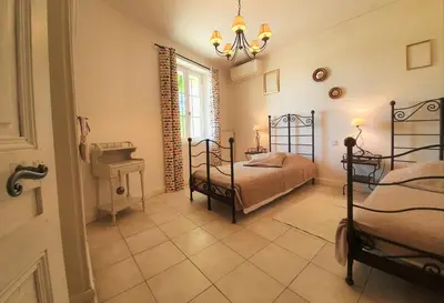 a bedroom with two twin beds and a chandelier at Côté Provence in Le Thor