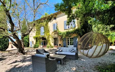 a chair and a couch in front of a house at Côté Provence in Le Thor