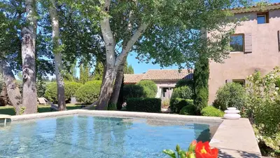 a swimming pool in front of a house with trees at Le Mas Des Bardes in Pernes-les-Fontaines